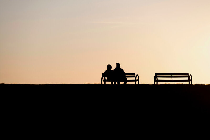 Zwei Menschen sitzen auf der Bank, im Hintergrund der Himmel