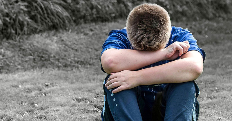 Ein Kind vergräbt seinen Kopf traurig in seinen Armen