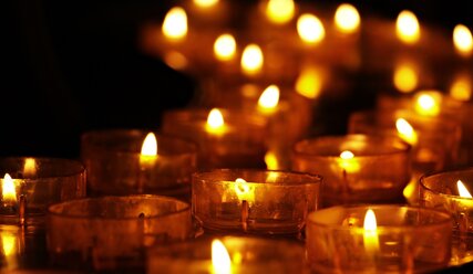Eine Reihe von brennenden Kerzen in einer Kirche - Copyright: NoName_13 / pixabay