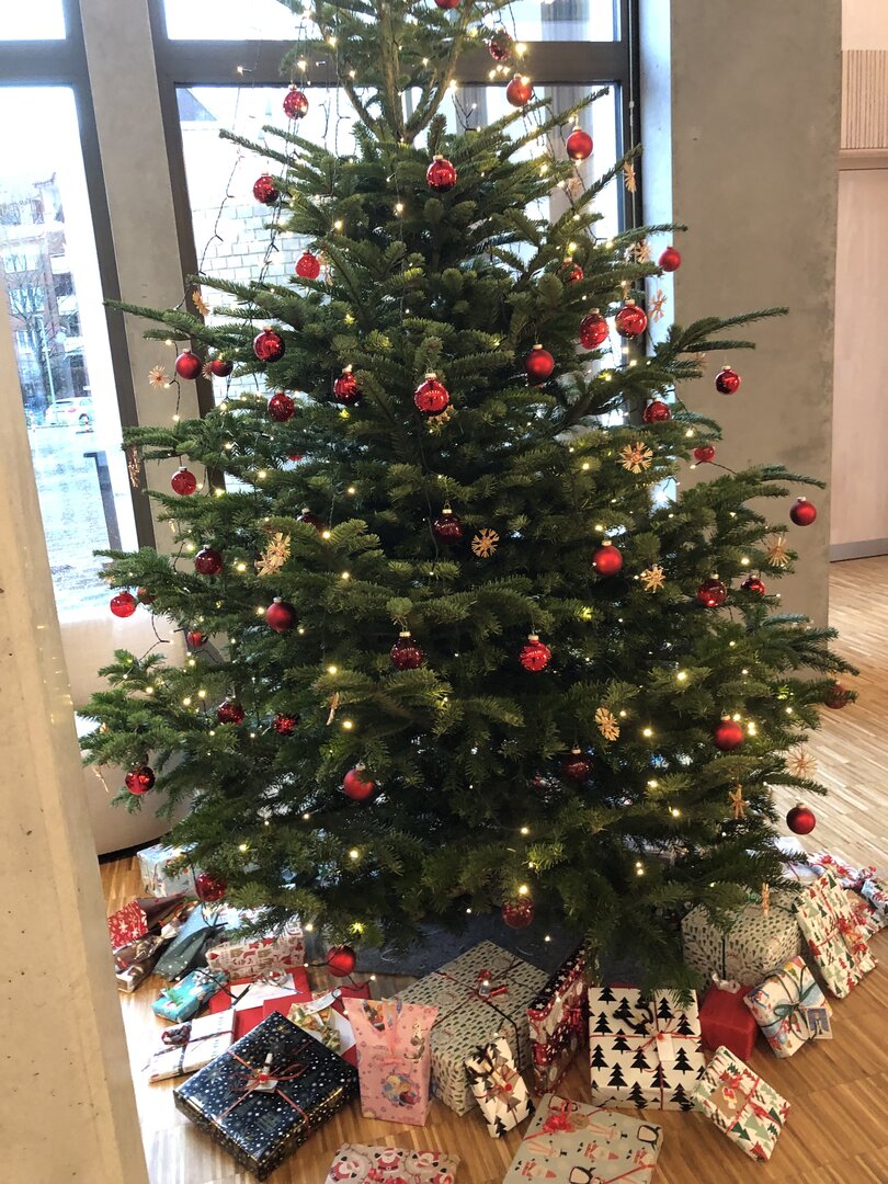 Ein vollgeschmückter Weihnachtsbaum umringt von zahlreichen bunt-verpackten Geschenken