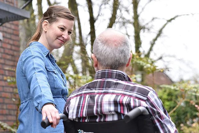 Eine Frau im Gespräch mit einem älterem Mann im Rollstuhl.