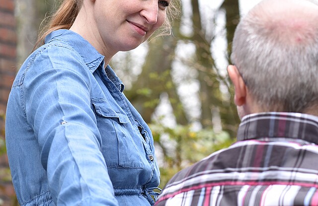 Eine Frau im Gespräch mit einem älterem Mann im Rollstuhl.