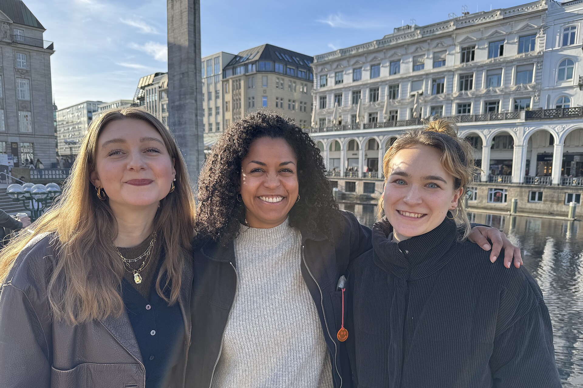 Drei Frauen stehen nebeneinander und lächeln in die Kamera