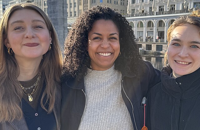 Drei Frauen stehen nebeneinander und lächeln in die Kamera