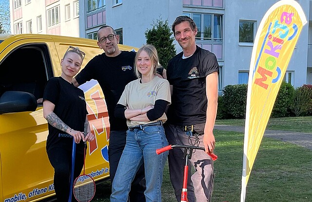 Die Mitarbeitenden von Mokija stehen vor dem gelben Auto