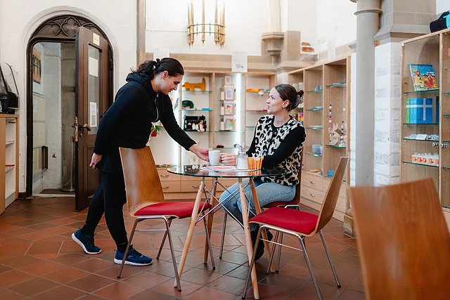 Einer Person wird im inklusiven Café der Hamburger Hauptkirche St. Petri ein Getränk serviert