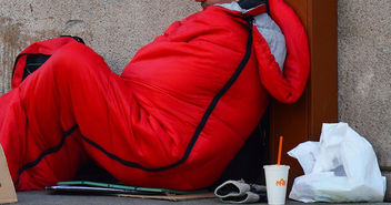 Obdachloser sitzt im winter auf der Straße, in einem dicken Schlafsack - Copyright: © Creative Commons