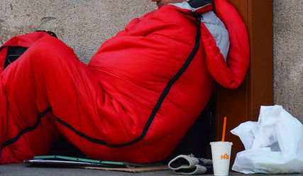 Obdachloser sitzt im winter auf der Straße, in einem dicken Schlafsack - Copyright: © Creative Commons