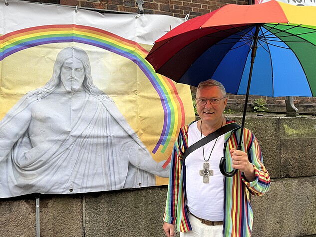 Pastor Sieghard Wilm vor einem Banner mit Jesus