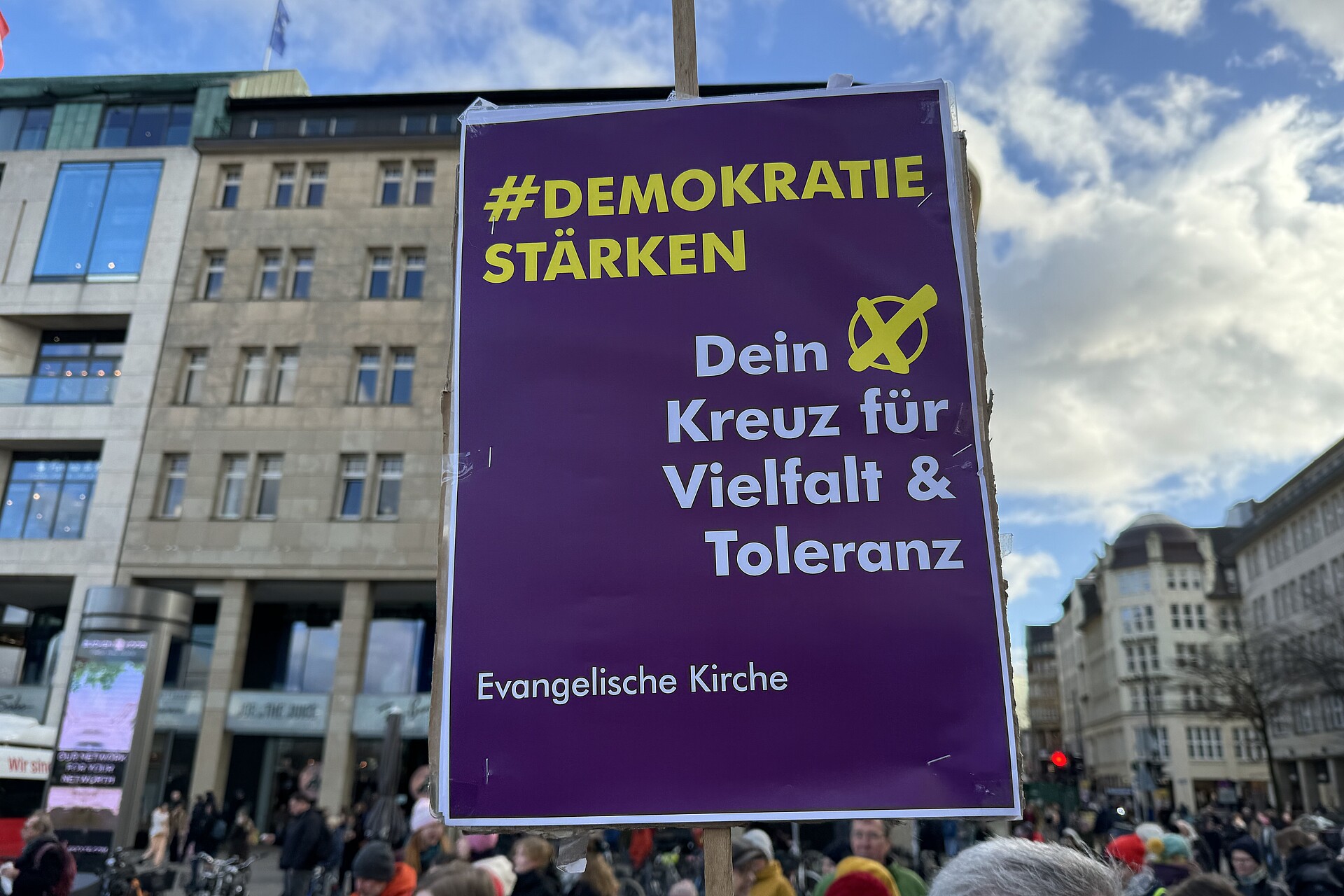 Auf einer Demonstration in Hamburg wird ein Schild hochgehalten mit der Aufschrift "Demokratie stärken, dein Kreuz für Vielfalt und Toleranz"