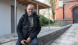 Pastor Martin Kaiser freut sich über die neuen Sanitäranlagen (links im Bild). Rechts ist der rückwärtige Eingang der Kreuzkirche zu sehen. - Copyright: © Hagen Grützmacher