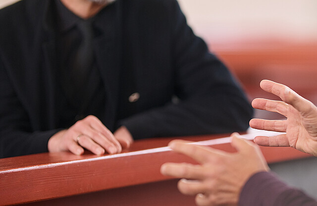 Ein Pastor im Seelsorge-Gespräch mit einem älterem Ehepaar in der Kirche.