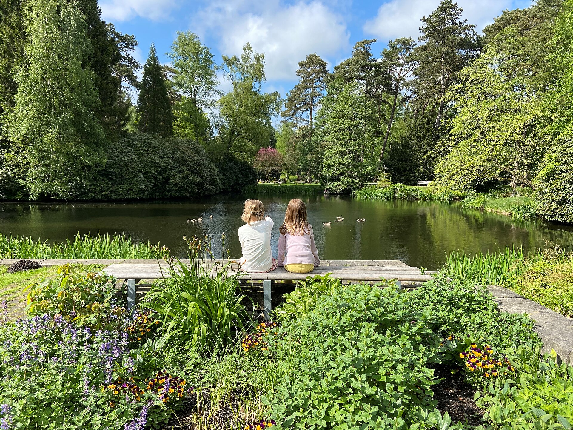 Zwei Kinder sitzen vor einem See im Ohlsdorfer Friedhof