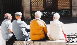 Vier Senioren die auf Steinpollern auf dem Marktplatz sitzen und sich unterhalten - Copyright: Beth Macdonald