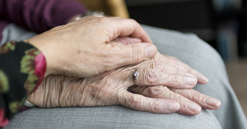 Eine Frau hält die Hand einer älteren Angehörigen