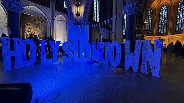 Holy Slow Down steht als Text im Raum einer Kirche