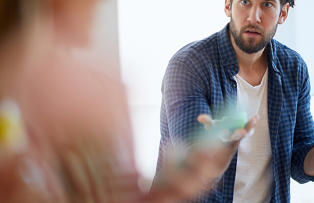 Ein junger Mann streitet mit seiner Freundin in der Küche.