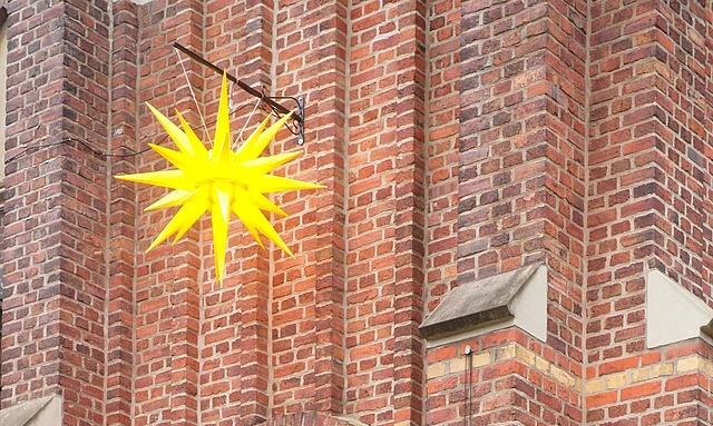 Herrnhuther Weihnachtsstern vor roter Backsteinkirche.