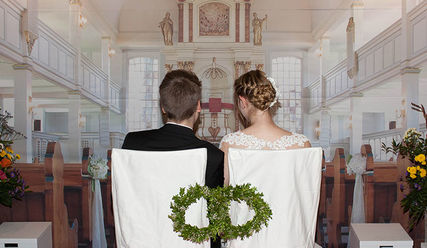 Ein angehendes Hochzeitspaar nimmt auf den Stühlen vor der Bannerwand Platz, die den Altarraum abbildet.  - Copyright: Thomas Krätzig