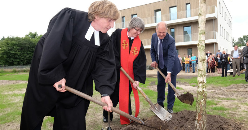 Pastor Oliver Spies, Pastorin Corinna Peters-Leimbach und Bürgermeister Olaf Scholz (v.l.) pflanzen einen Baum auf dem Gelände des neuen Wohnquartiers