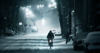 Ein Mensch fährt durch eine verschneite Straße auf dem Fahrrad - Copyright: Marcel Köhler / pexels