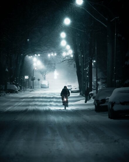 Ein Mensch fährt durch eine verschneite Straße auf dem Fahrrad