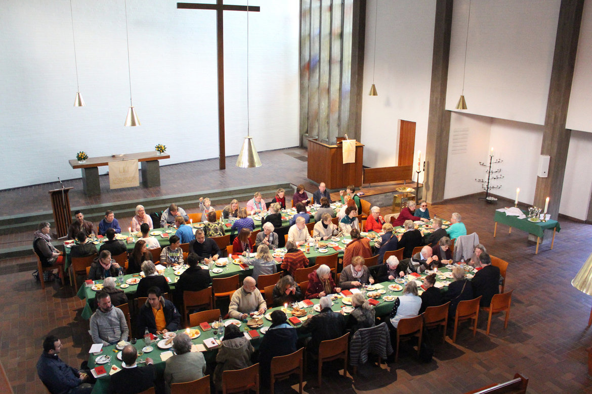 Menschen an gedeckten Tischen in der St. Johanniskirche Harburg