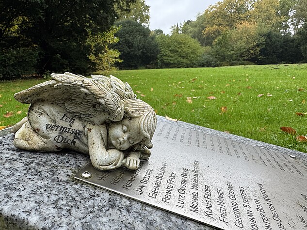Eine Engelsstatue auf einem Grabstein mit Namen Verstorbener