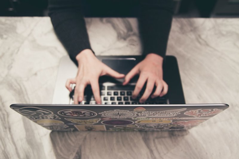 Person tippt auf einer Laptop-Tastatur