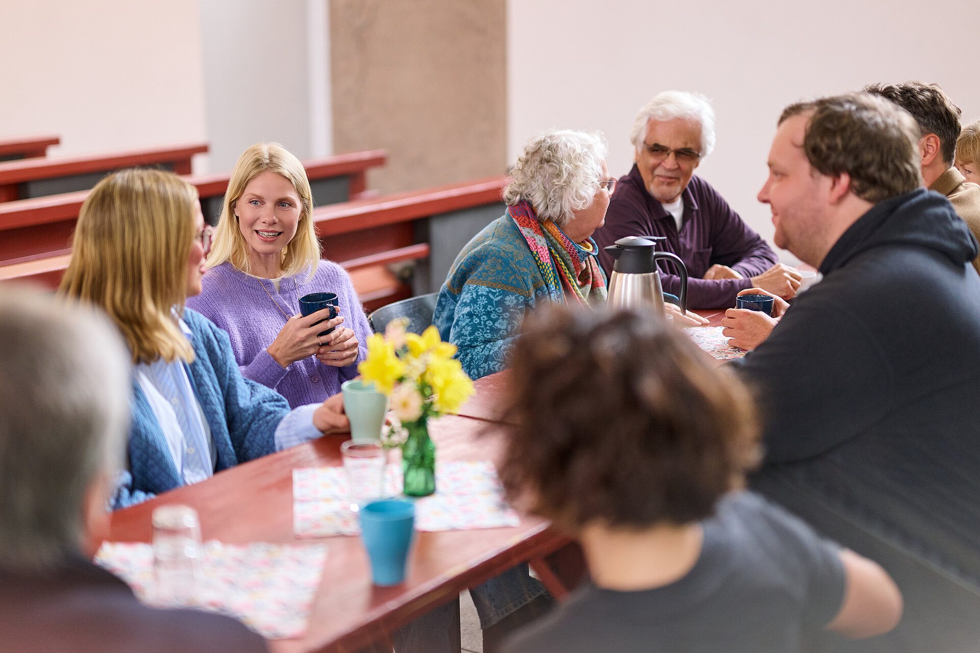 Eine Gruppe von Menschen sitzt zusammen am Tisch und unterhält sich angeregt