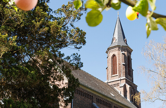 Eine Kirche, davor ein Baum mit Ostereiern