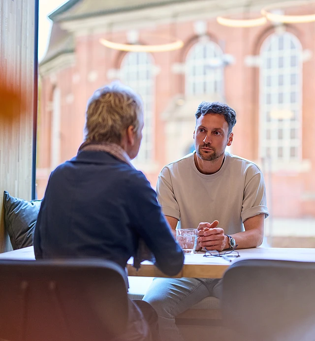 Ein Mann hat ein Seelsorgegespräch mit einer anderen Person