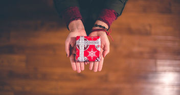 Zwei Hände halten ein Weihnachtsgeschenk - Copyright: Ben White / Unsplash