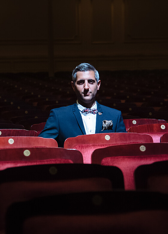 Ein Mann sitzt in einem Kinosaal auf einem roten Sessel