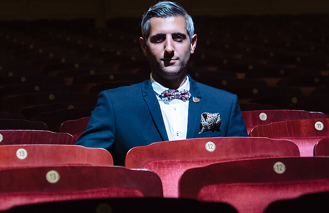 Ein Mann sitzt in einem Kinosaal auf einem roten Sessel