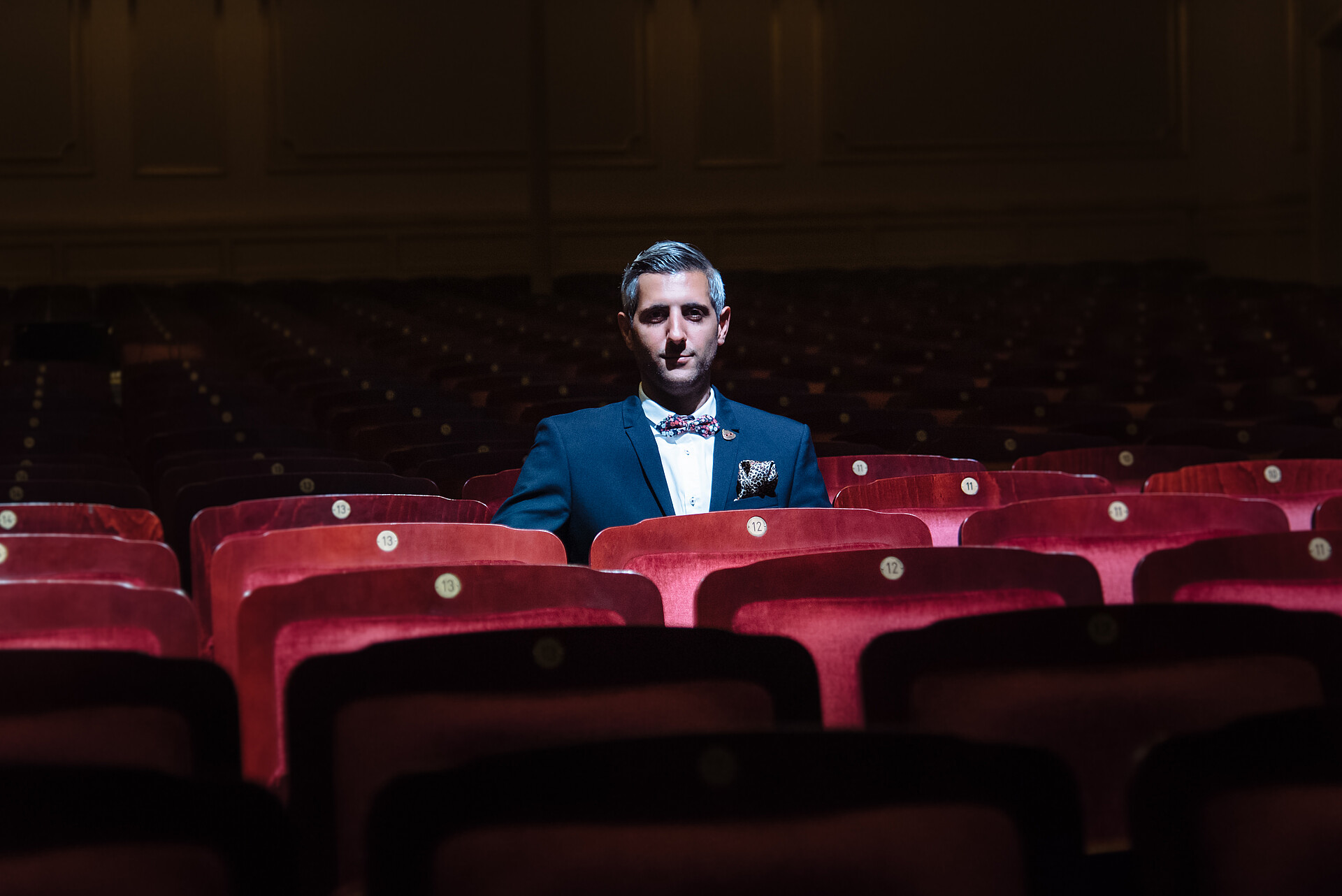 Ein Mann sitzt in einem Kinosaal auf einem roten Sessel