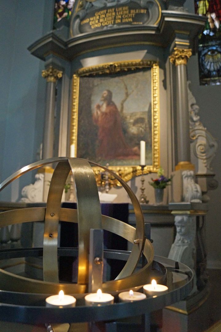 Kerzen leuchten am Kerzenbaum, im Hintergrund der Altar mit dem betenden Jesus
